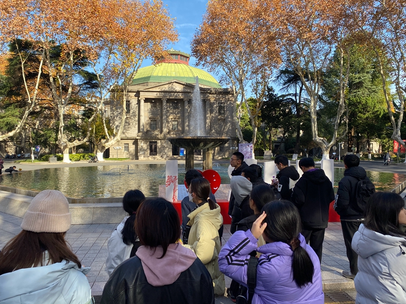 一群年轻学生集结在大礼堂前的喷水池广场上，听一位citywalk领队介绍东南大学四牌楼校区    摄影/佟鑫